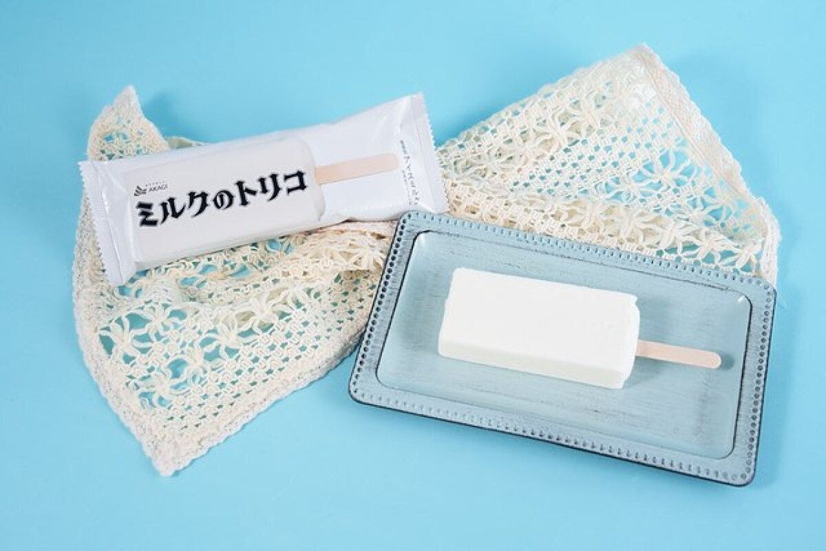 袋入りのミルクのトリコと、青い皿に置かれた白いアイスバー 袋入りのミルクのトリコと、青い皿に置かれた白いアイスバー
