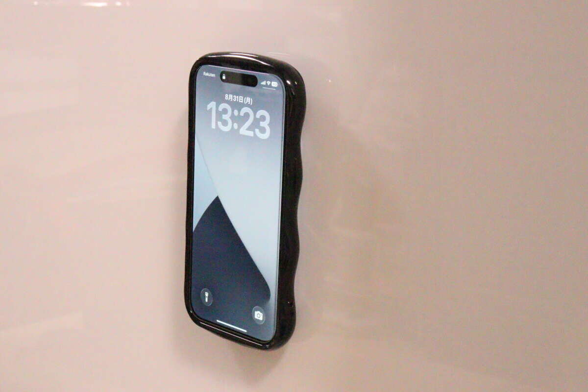 壁にシリコン携帯吸着マットで固定された黒いスマホ