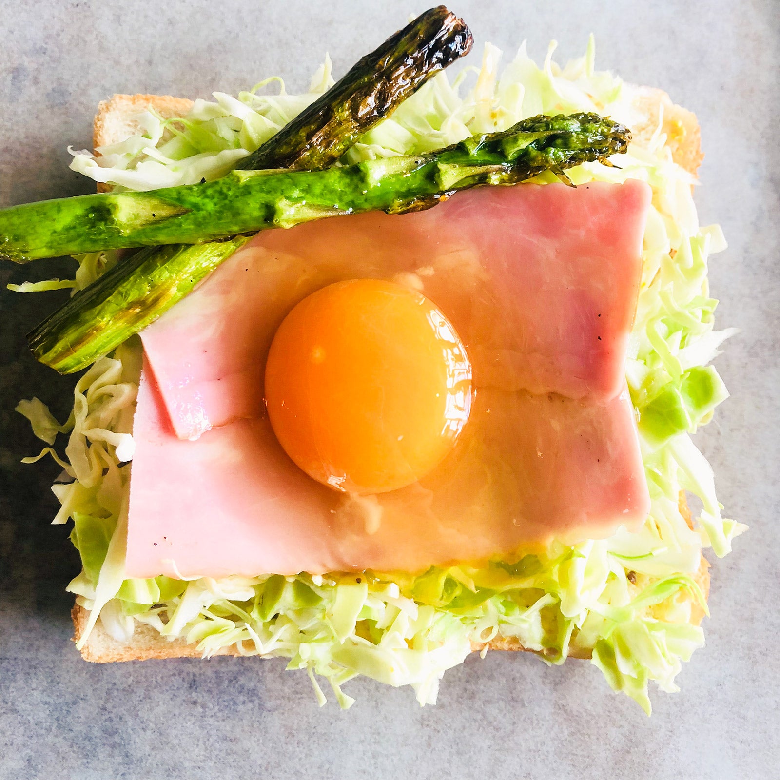 手順4：スライスベーコンを二枚のせ、卵を割る／画像提供：柏原歩