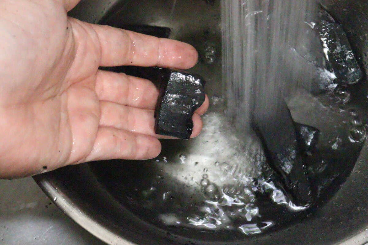 シンクで竹炭を流水で洗っている手のアップ