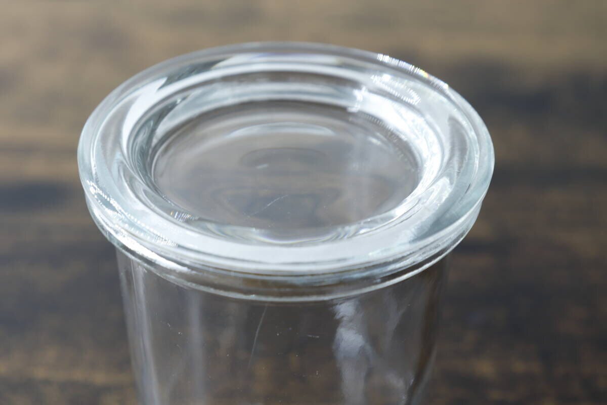 透明なガラス容器の蓋のアップ。シンプルなデザインで、厚みのあるガラス製。 透明なガラス容器の蓋のアップ。シンプルなデザインで、厚みのあるガラス製。
