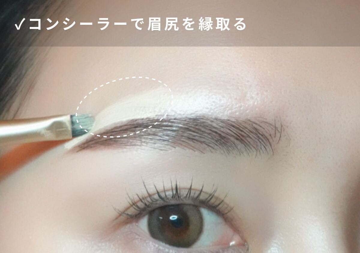 コンシーラーブラシで眉尻の輪郭を縁取って整えている目元のアップ写真