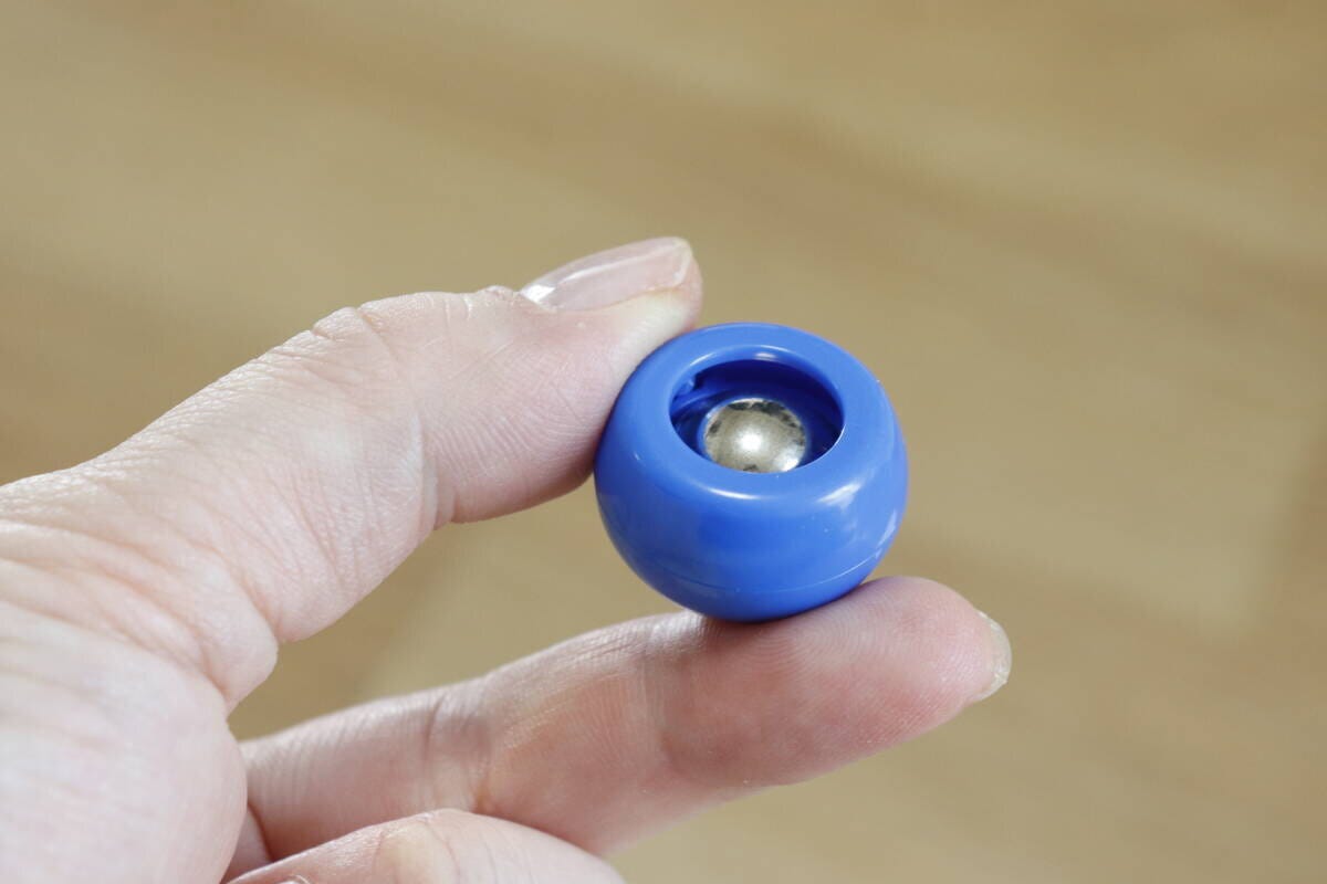 指で持った青いカーリングストーンの裏側にある鉄玉 指で持った青いカーリングストーンの裏側にある鉄玉