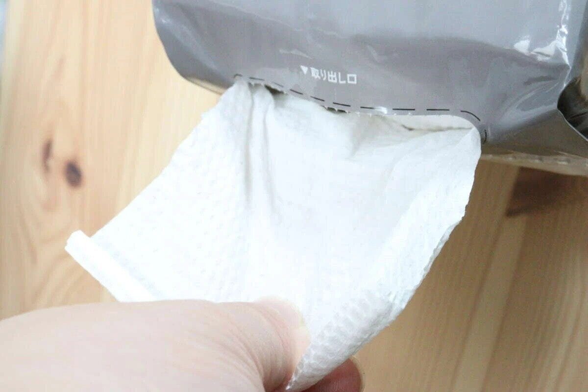 パッケージの取り出し口からペーパータオルを一枚引き出す手 パッケージの取り出し口からペーパータオルを一枚引き出す手