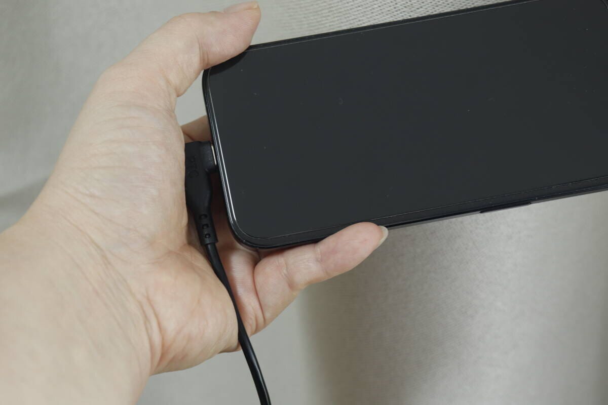 L字型コネクタをスマホに接続し横向きに持っている手元 L字型コネクタをスマホに接続し横向きに持っている手元