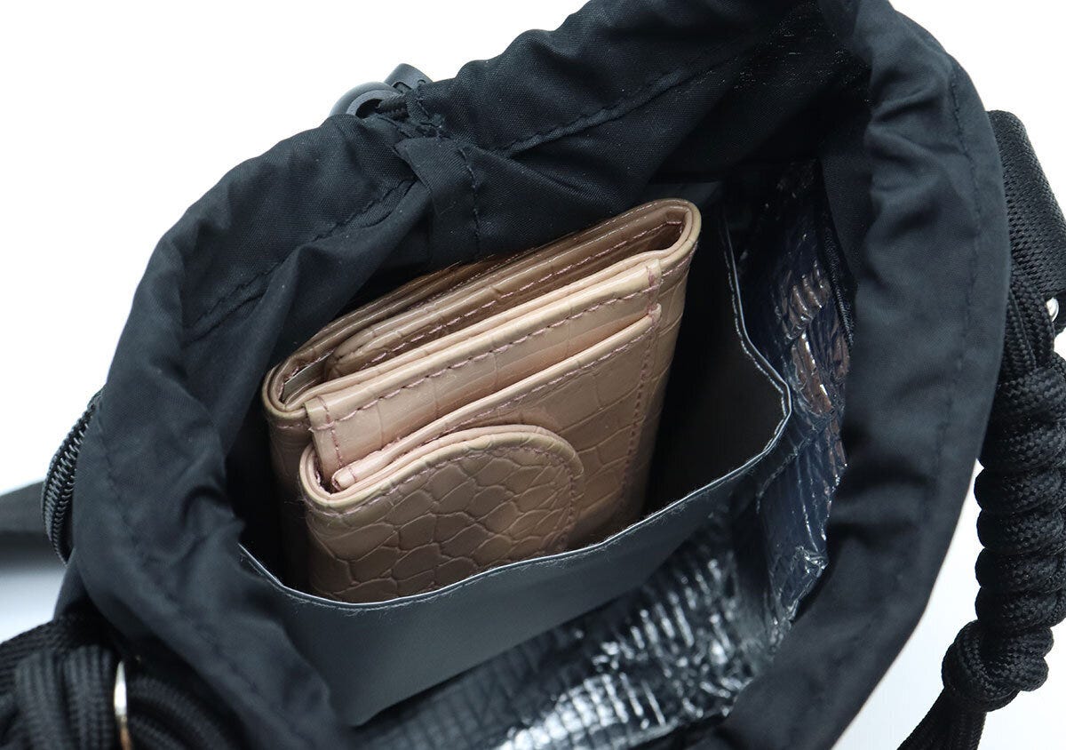 ショルダーバッグの内ポケットに二つ折り財布を収納している様子