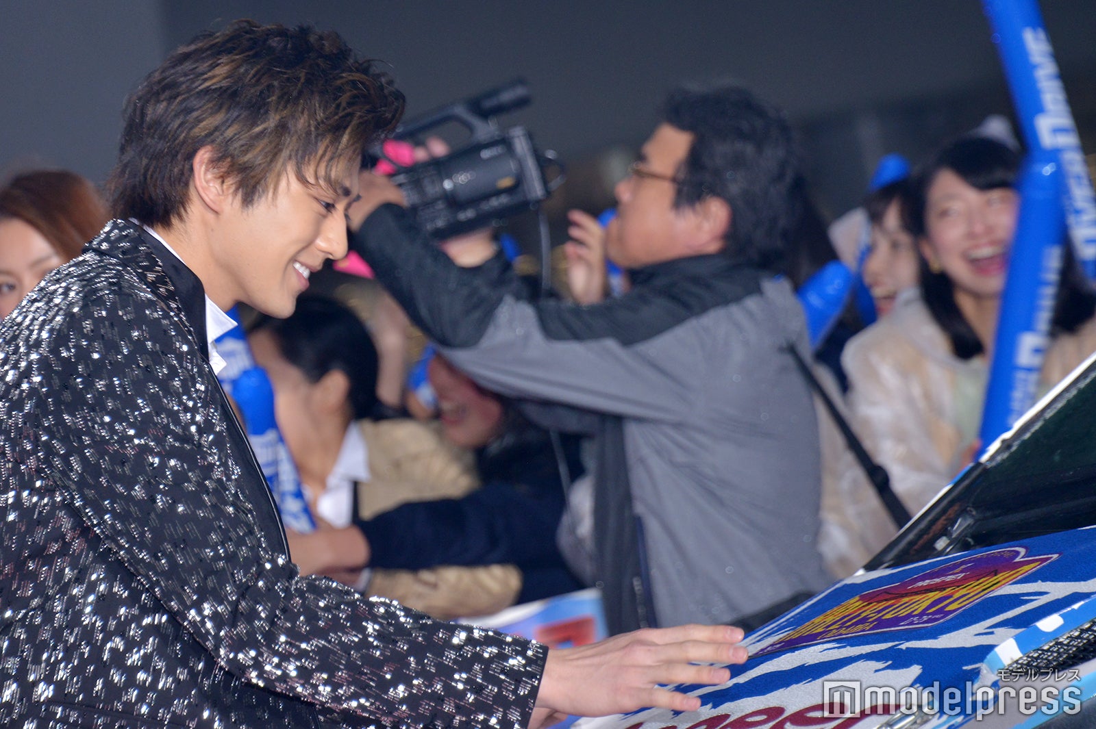 本編で使用された車を基に作られたラリーカーと対面し、ボンネットの水を払う新田真剣佑 （C）モデルプレス