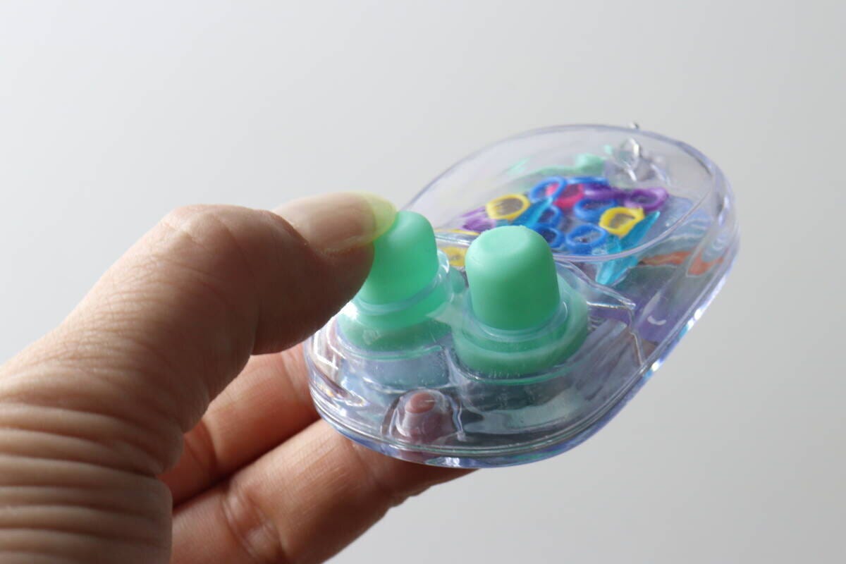 指でミニウォーターゲーム機の水色のボタンを押し、水流を起こしている 指でミニウォーターゲーム機の水色のボタンを押し、水流を起こしている