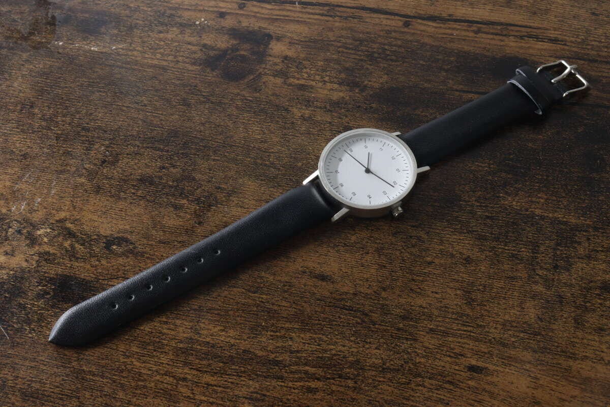 木目調のテーブルに置かれた黒いベルトのシンプルウォッチ 木目調のテーブルに置かれた黒いベルトのシンプルウォッチ