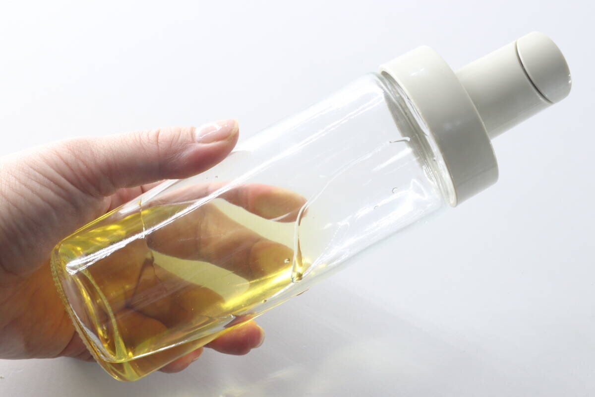 食用油が入ったオイルボトルを手に持ち、残量を確認している 食用油が入ったオイルボトルを手に持ち、残量を確認している