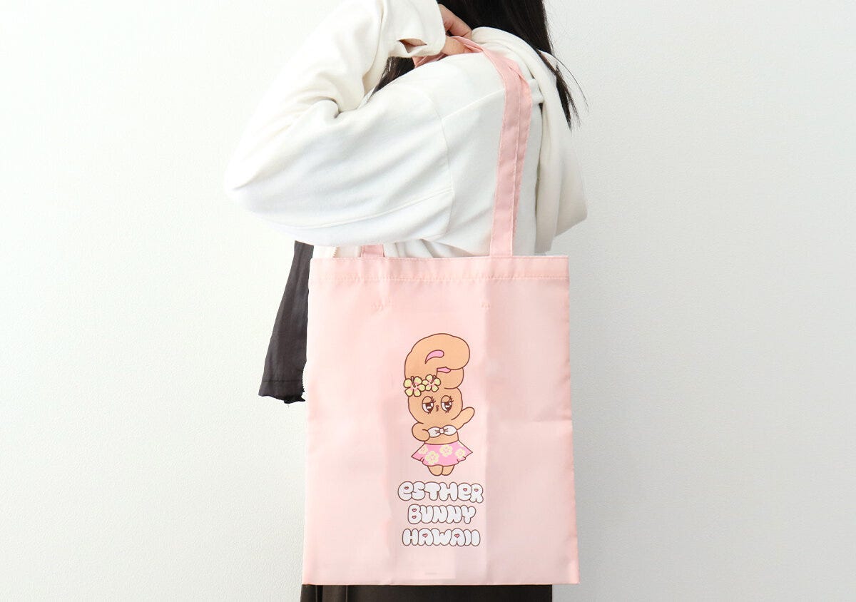 白いパーカーの女性がピンクのトートバッグを肩掛けしている後ろ姿