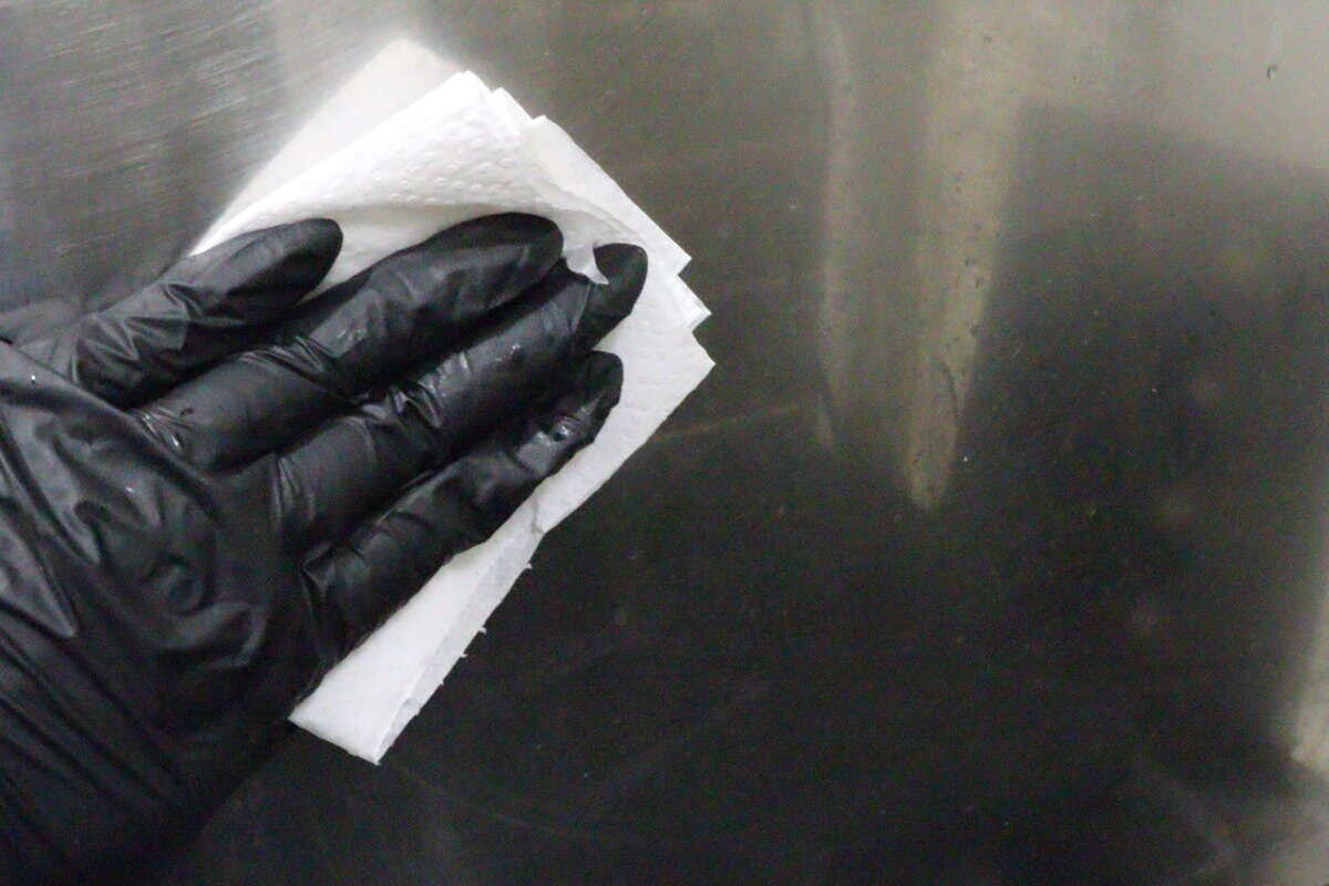 洗剤を含ませたキッチンペーパーでキッチンの壁を拭いている状態 洗剤を含ませたキッチンペーパーでキッチンの壁を拭いている状態