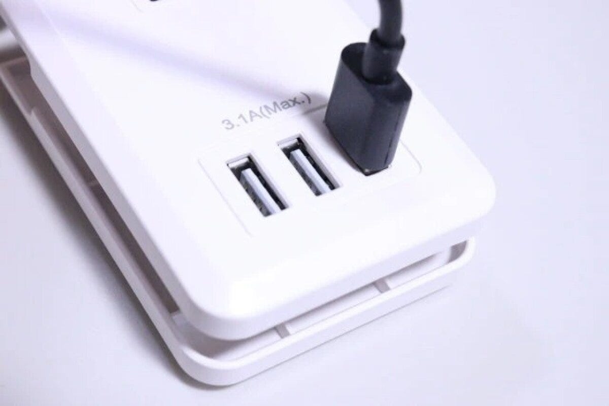 白いコンセントタップのUSBポートに黒いケーブルが差し込まれている