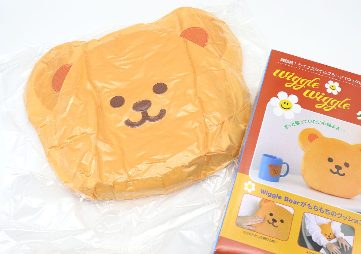 圧縮された状態で袋に入ったウィグルベアのもちもちクッションと、ムック本のパッケージ