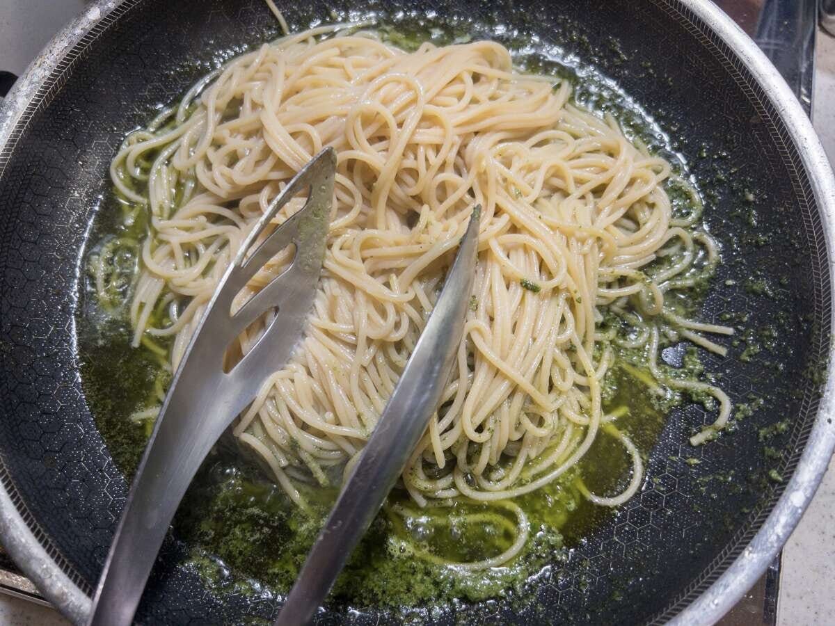 フライパンの中でしそベーゼソースと茹でたパスタをトングで和えている様子 フライパンの中でしそベーゼソースと茹でたパスタをトングで和えている様子