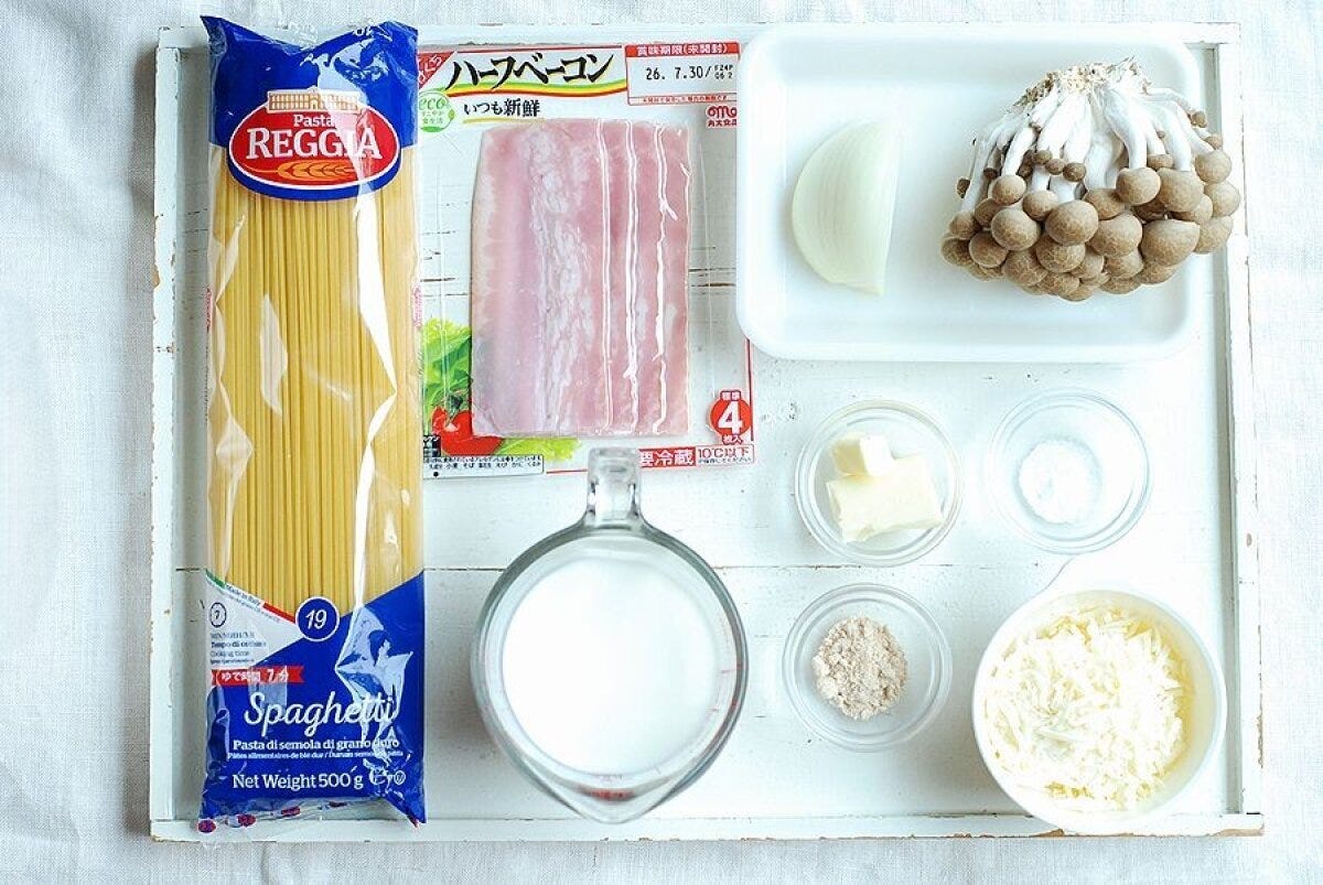 白いトレイに並べられたパスタ、きのこ、ベーコンなどパスタの材料。 白いトレイに並べられたパスタ、きのこ、ベーコンなどパスタの材料。