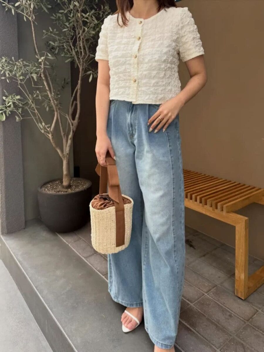 白のショート丈カーデとワイドデニムを着用しカゴバッグを持つ女性 白のショート丈カーデとワイドデニムを着用しカゴバッグを持つ女性