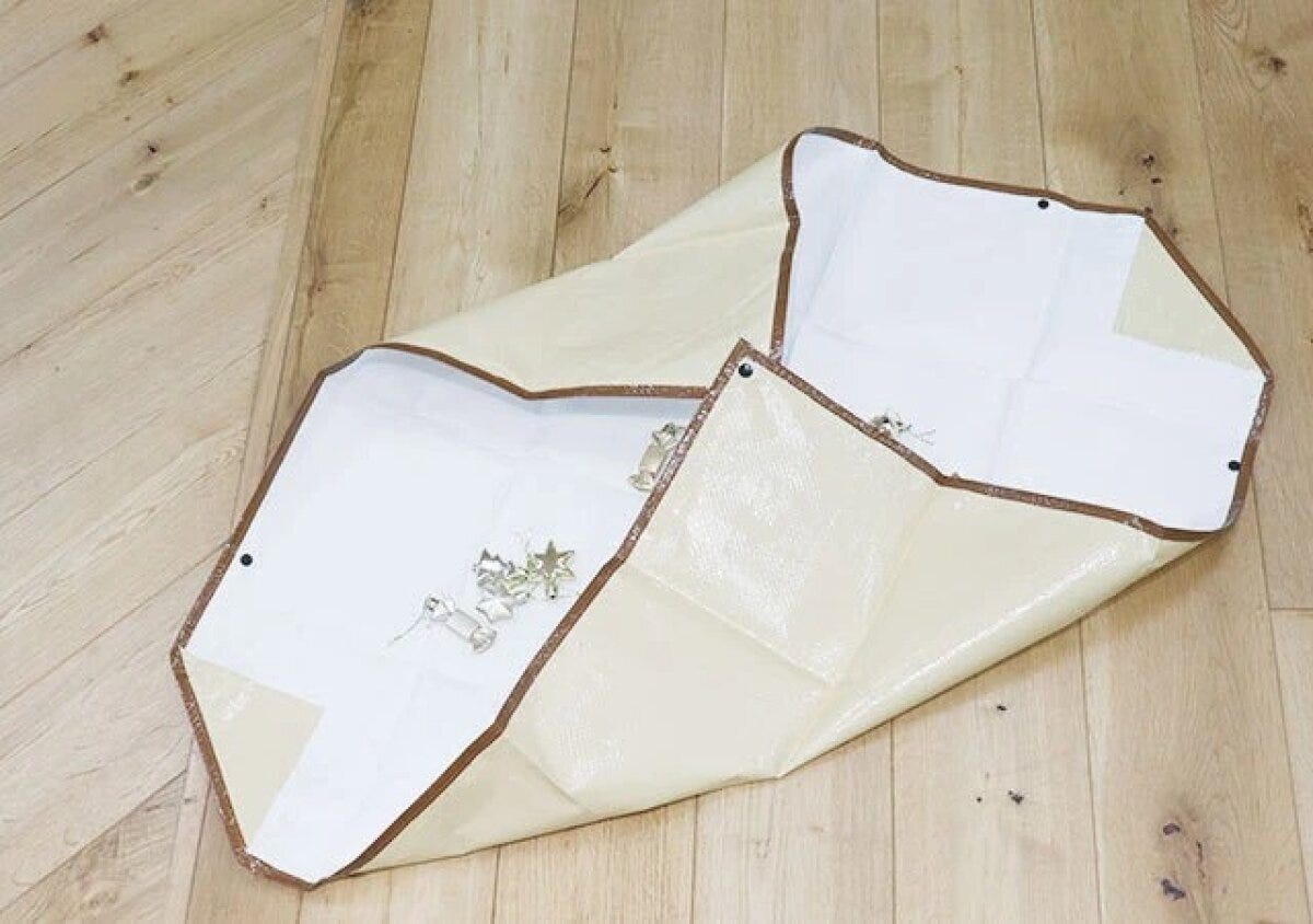 お片付け袋の対角線上のボタンを留めて折りたたむ様子