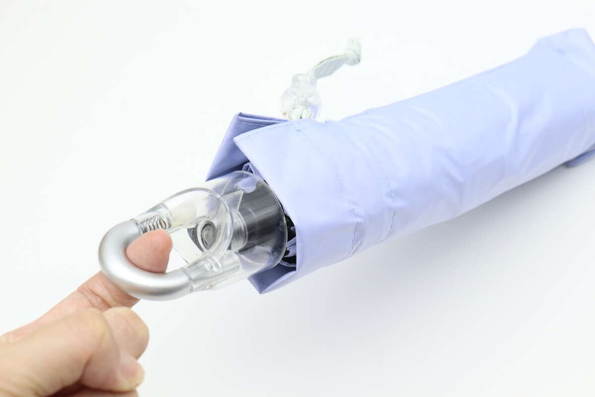 折りたたみ傘の持ち手にあるカラビナ部分を指で触っている