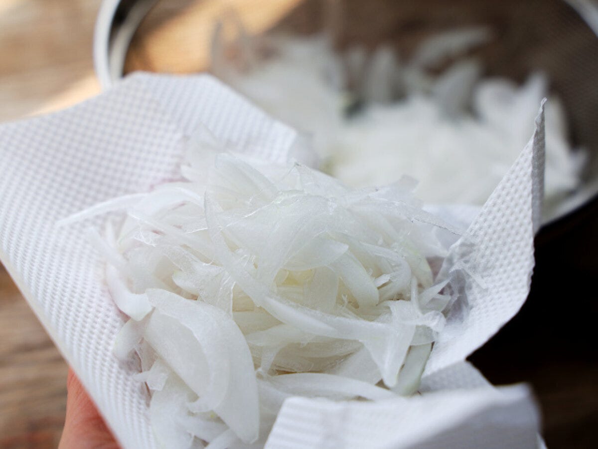 キッチンペーパーで水気を切った新玉ねぎスライスを手で持っている様子 キッチンペーパーで水気を切った新玉ねぎスライスを手で持っている様子