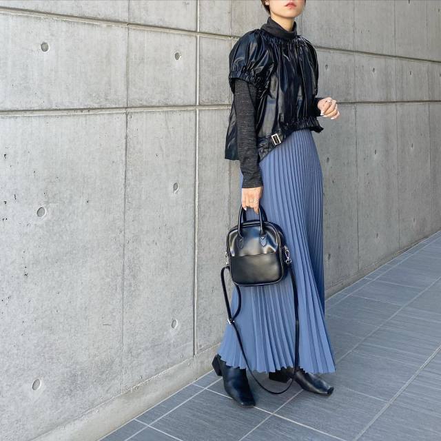 エコレザートップスにプリーツスカートを合わせたコーデ