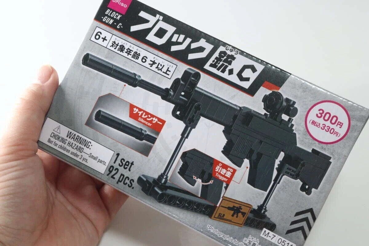 手に持ったダイソーのブロック銃パッケージ。サイレンサーや引き金の表示。 手に持ったダイソーのブロック銃パッケージ。サイレンサーや引き金の表示。
