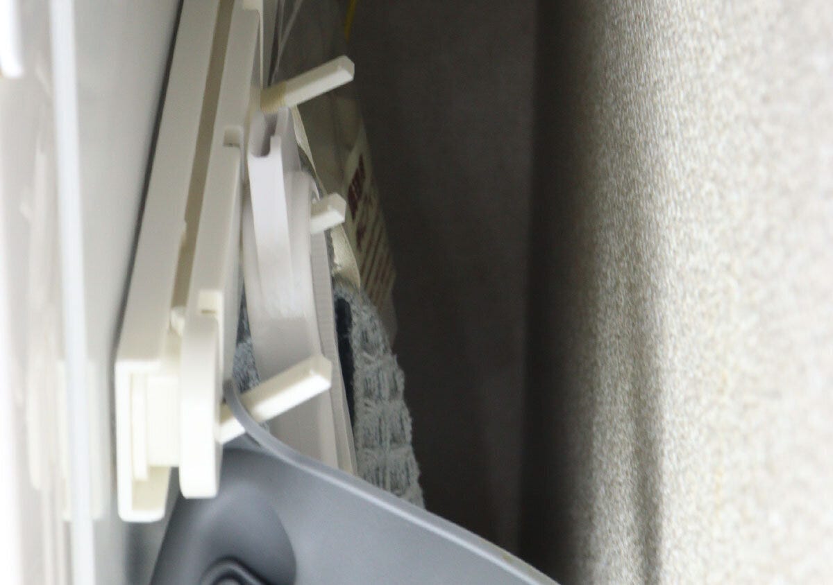狭い隙間に取り付けられた白い収納フックに、ミトンやタオルなどの小物が掛けられている様子 狭い隙間に取り付けられた白い収納フックに、ミトンやタオルなどの小物が掛けられている様子