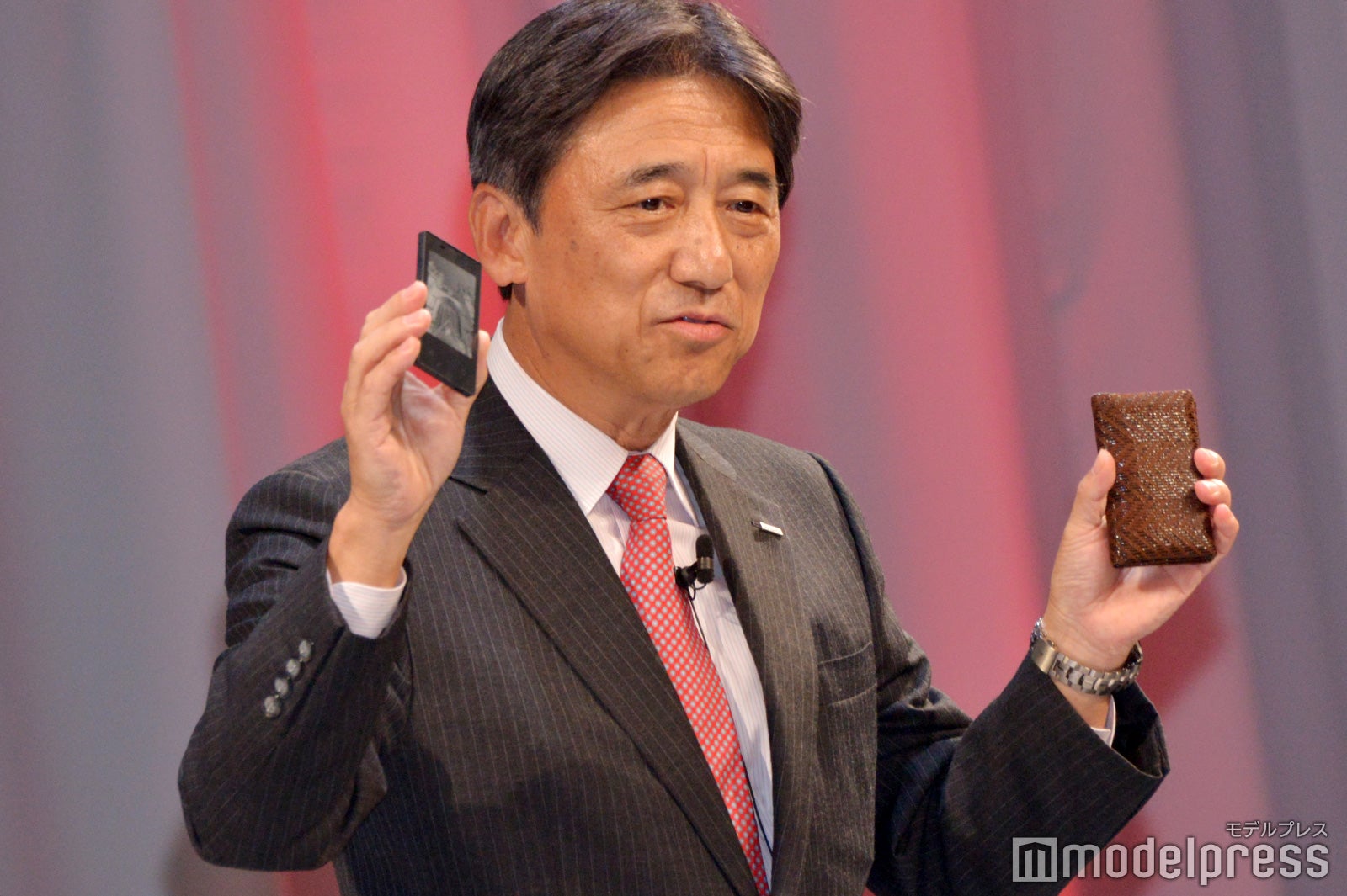 カードケータイ（左）を紹介する吉澤和弘社長（C）モデルプレス