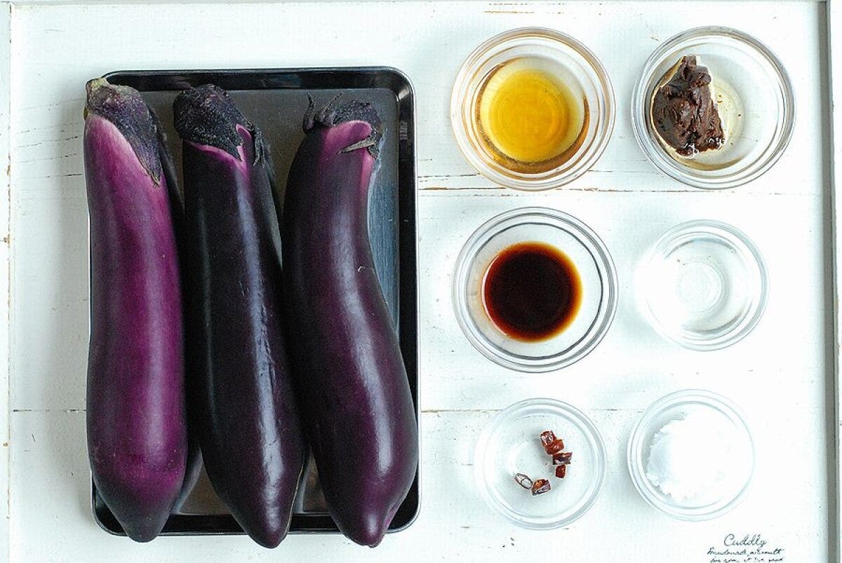 まな板の上に並べられたなす3本と、小皿に入った調味料の俯瞰写真 まな板の上に並べられたなす3本と、小皿に入った調味料の俯瞰写真