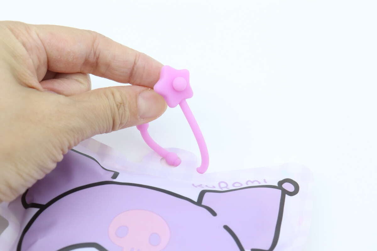指でピンクの星形ストラップを引っ張っている様子