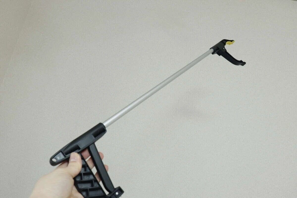 黒いマジックハンドを手に持ち、先端を上に向けている 黒いマジックハンドを手に持ち、先端を上に向けている