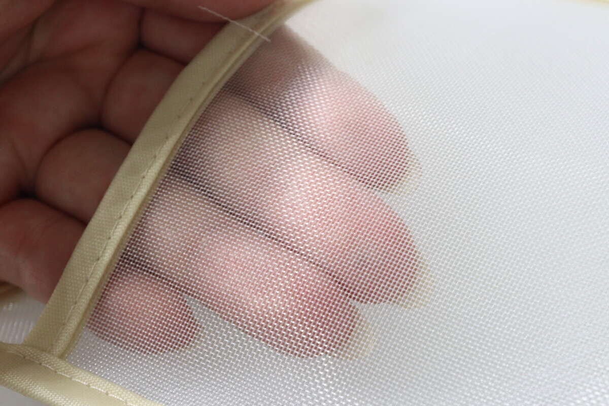 指でメッシュ素材を広げ、透け感と通気性を示している。 指でメッシュ素材を広げ、透け感と通気性を示している。