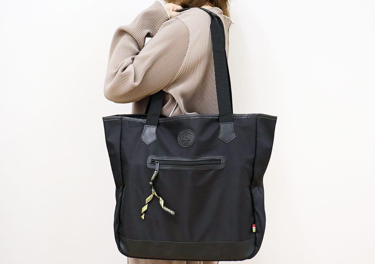 ベージュのトップスを着た女性がOrobiancoのトートバッグを肩掛けしている ベージュのトップスを着た女性がOrobiancoのトートバッグを肩掛けしている