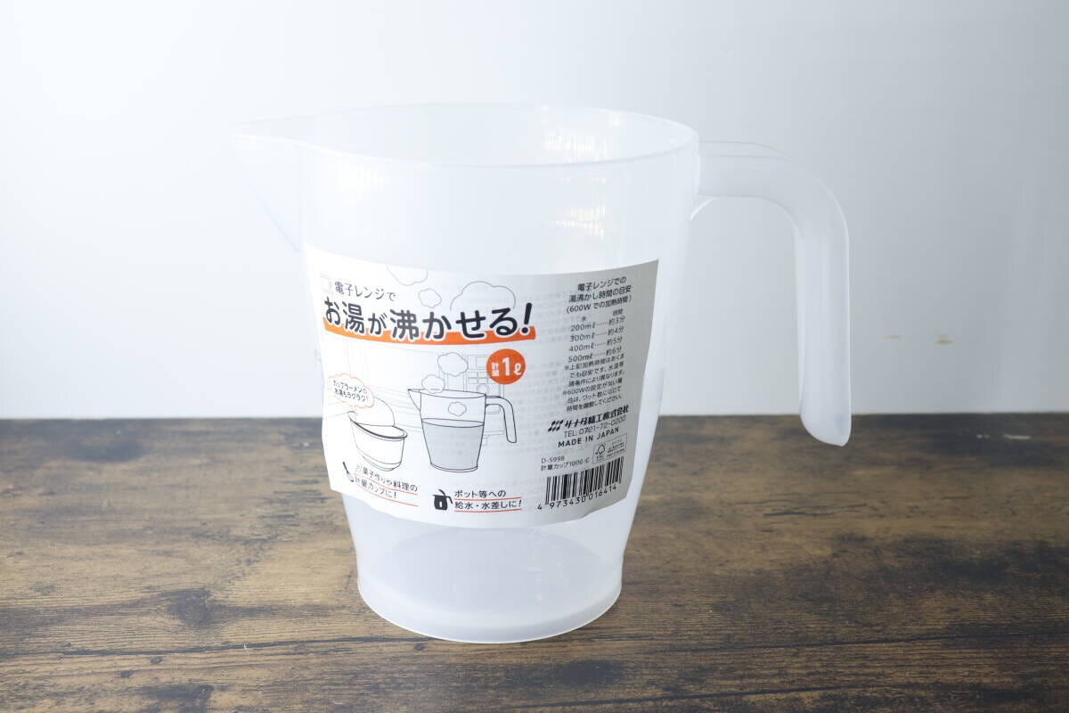 商品パッケージが貼られた透明な計量カップが木目のテーブルに置かれている 商品パッケージが貼られた透明な計量カップが木目のテーブルに置かれている