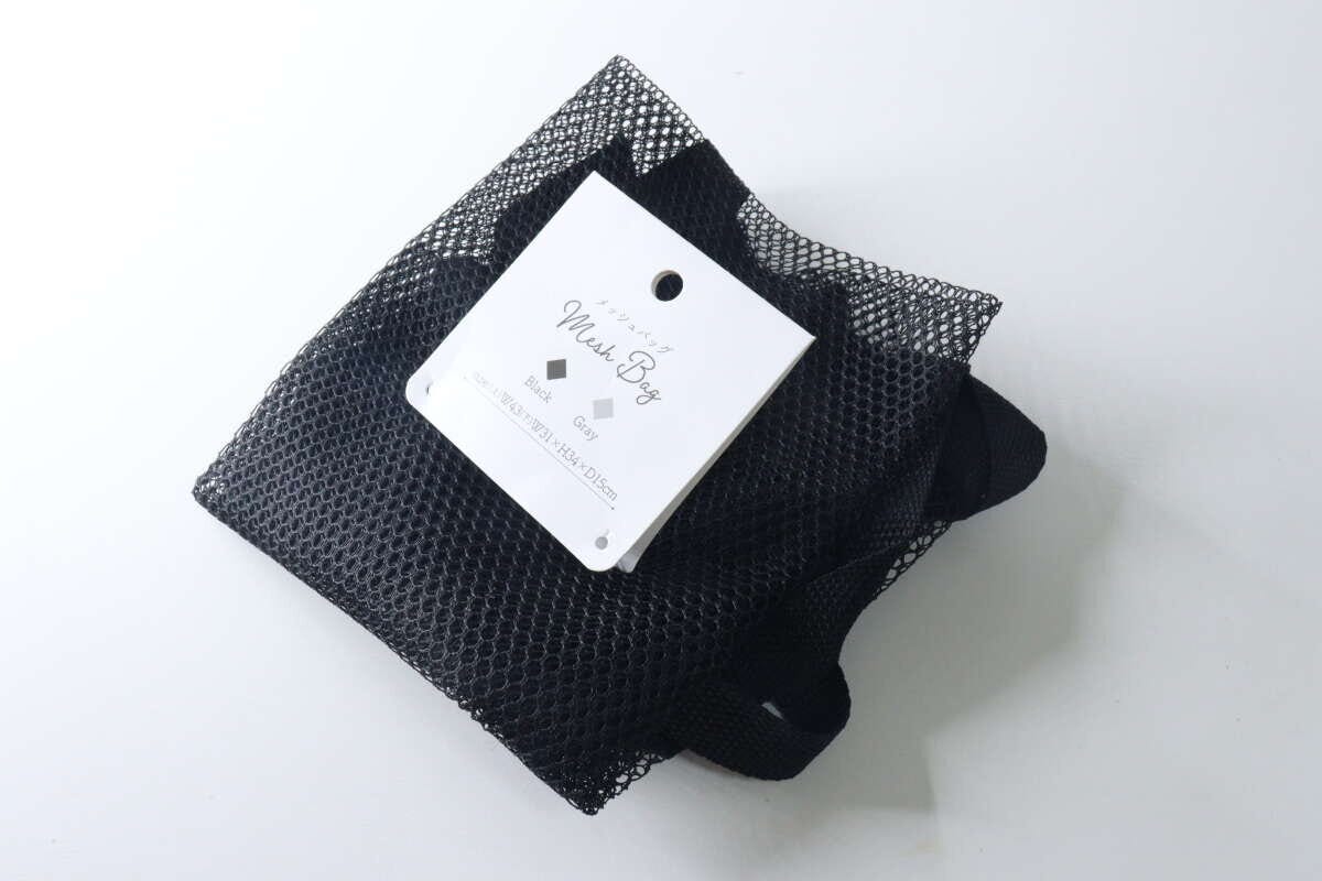 黒いメッシュバッグが畳まれた状態で置かれ、商品タグが上にある