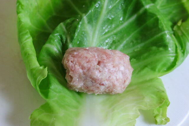 中央より手前側に肉だねを置き、手前のキャベツを巻き付けたら、左右の葉を折り込み、くるくると巻く。 中央より手前側に肉だねを置き、手前のキャベツを巻き付けたら、左右の葉を折り込み、くるくると巻く。