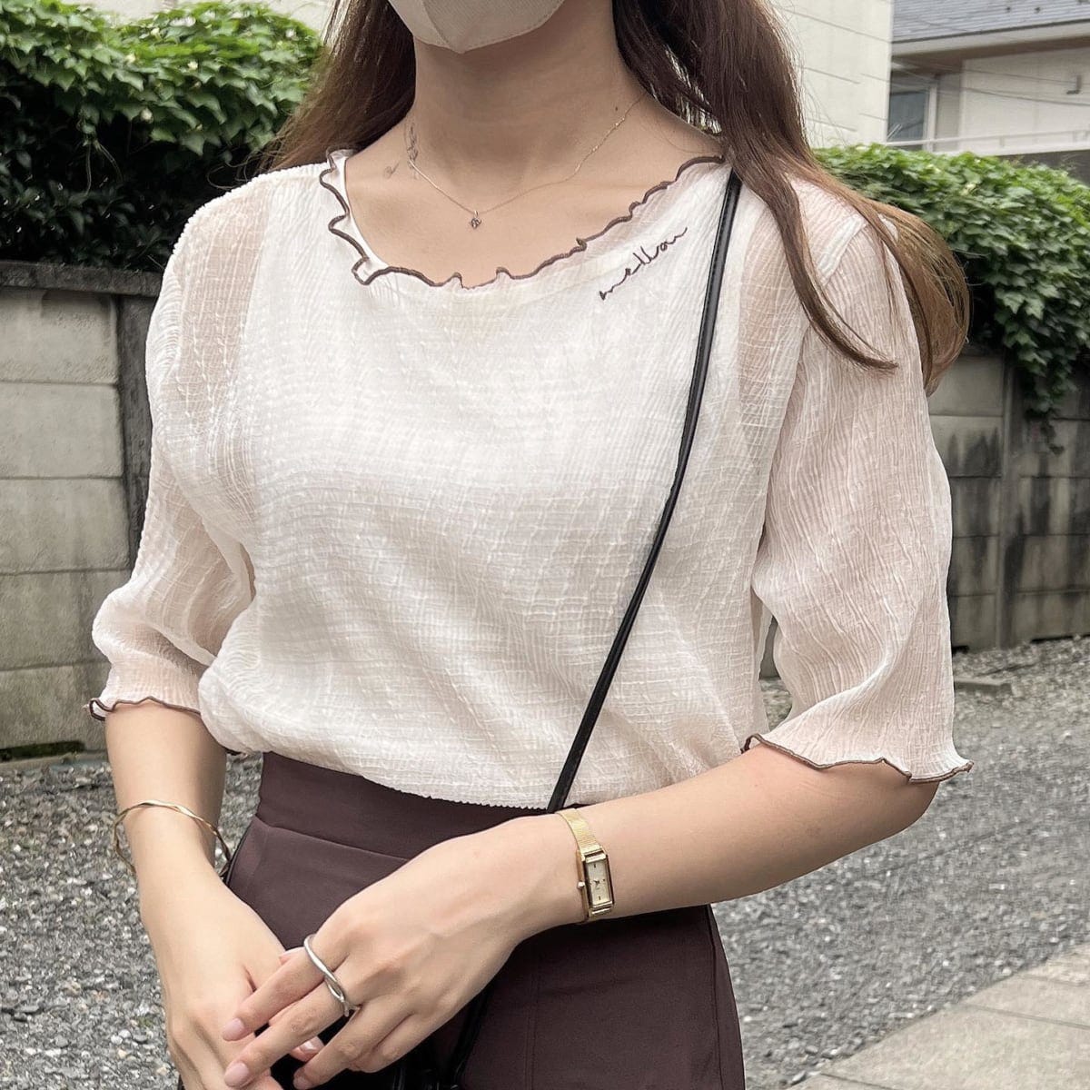 ベージュ系のバイカラーシアートップスを着ている女性