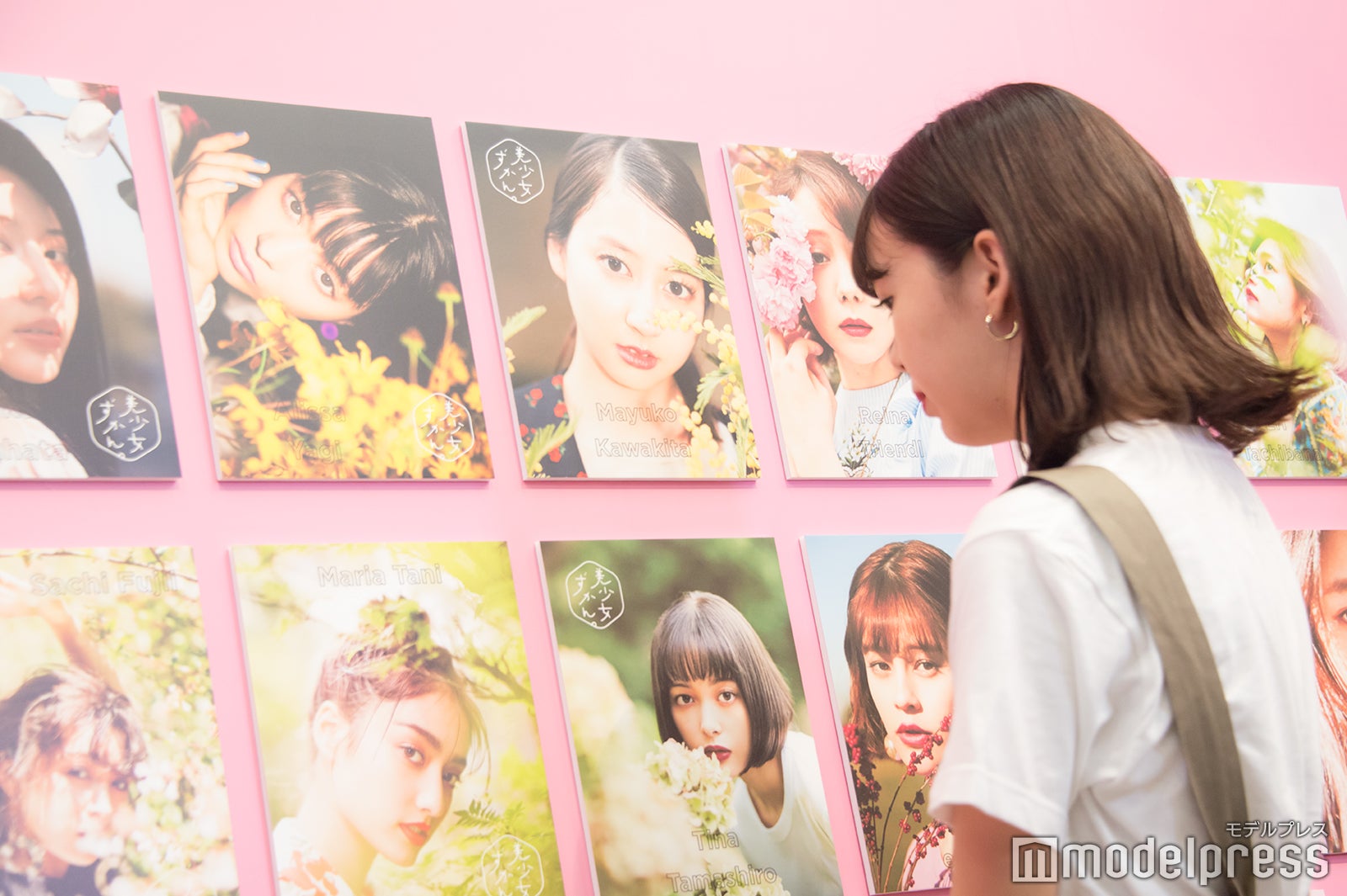 先輩たちの写真を眺める（C）モデルプレス