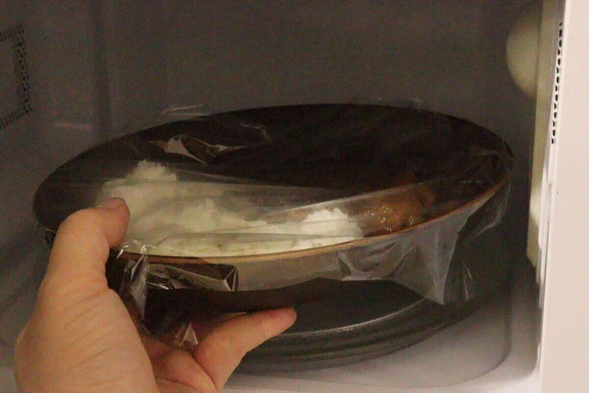 電子レンジの中で、ラップをかけた木目調オーバルプレートを温めている様子