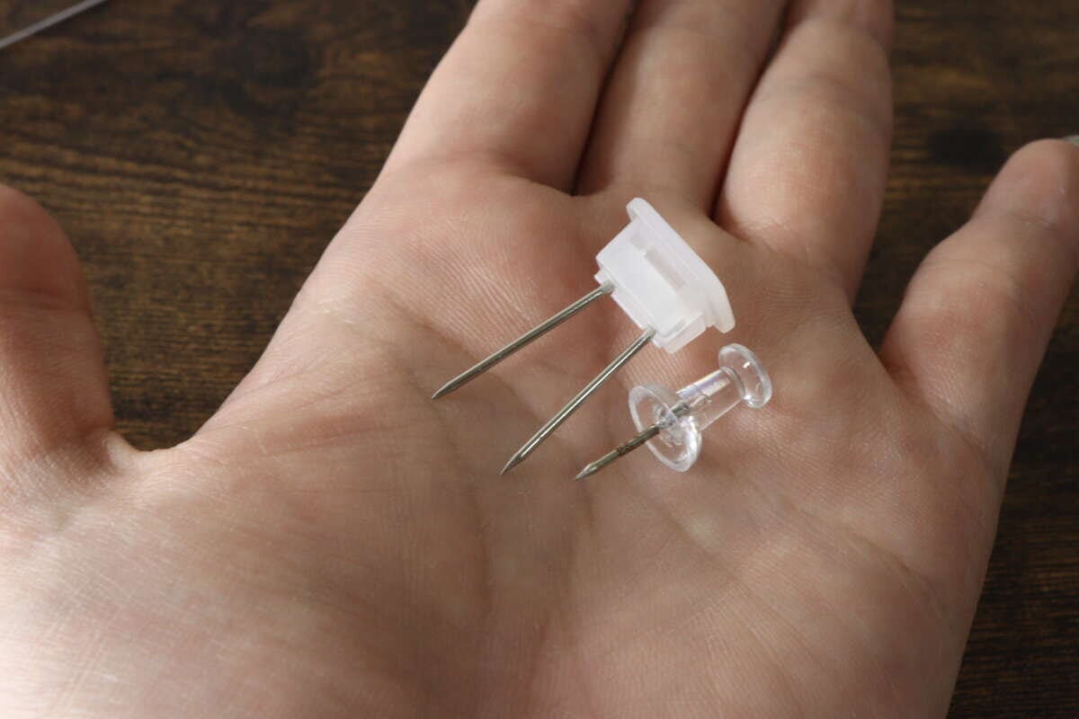 手の平の上に専用の長めのピンと通常のプッシュピンを並べて比較している様子 手の平の上に専用の長めのピンと通常のプッシュピンを並べて比較している様子