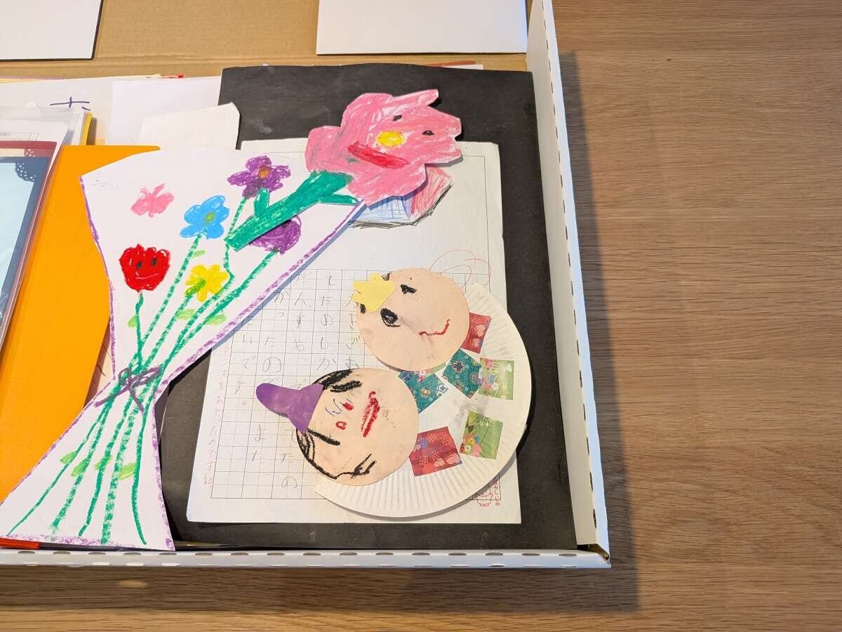 段ボール箱の中に、子どもが描いた花束の絵や顔の工作作品などが複数入っている