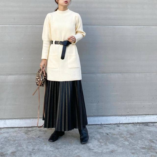 黒ベルト付きモックネック白ニットに黒のレザープリーツスカートを合わせ、スクエアブーツとレオパード柄ショルダーバッグをコーディネート