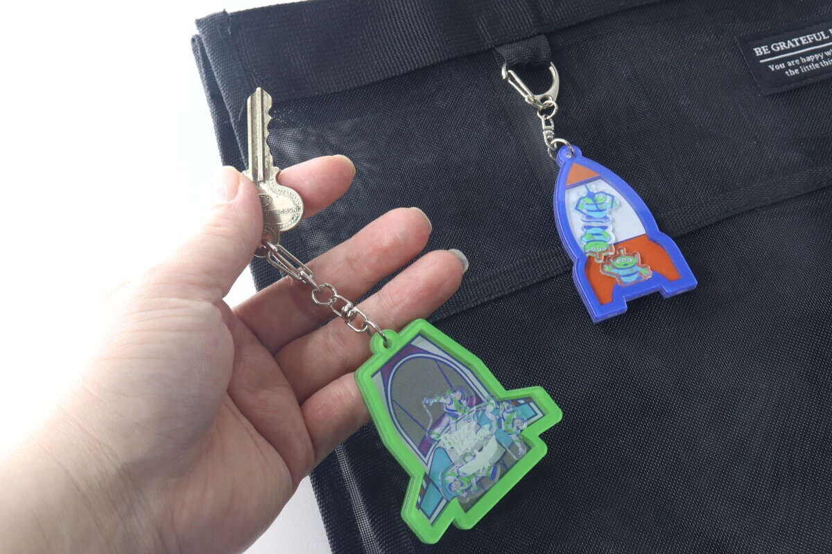 黒いバッグに付けられたキーホルダーと鍵を持つ手