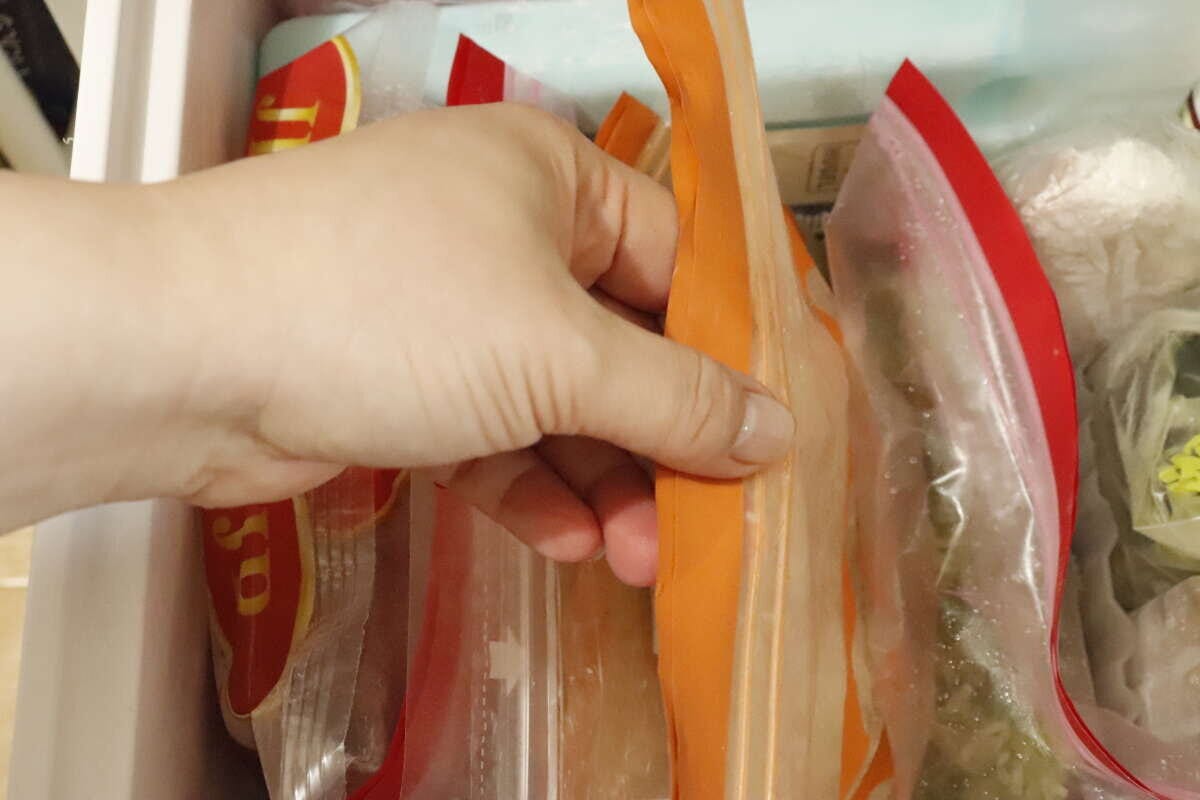 冷凍庫から立てて収納された冷凍食品を、手がスムーズに取り出している様子 冷凍庫から立てて収納された冷凍食品を、手がスムーズに取り出している様子