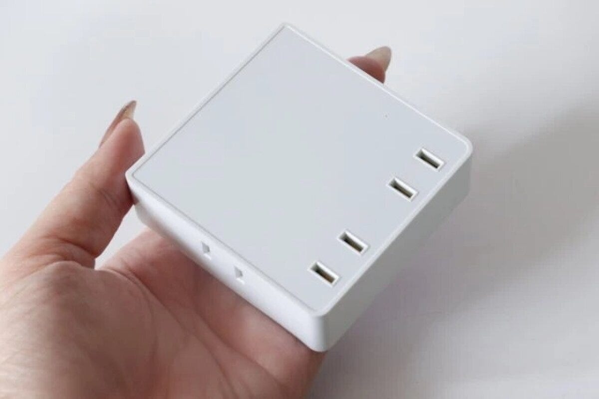 女性の手のひらに乗せられた白いスクエア型の4個口電源タップ