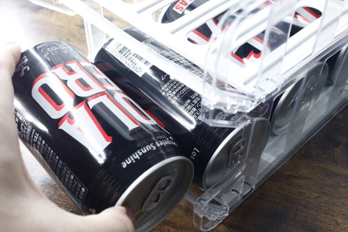缶ボトルホルダーから黒い缶ドリンクを取り出す手元