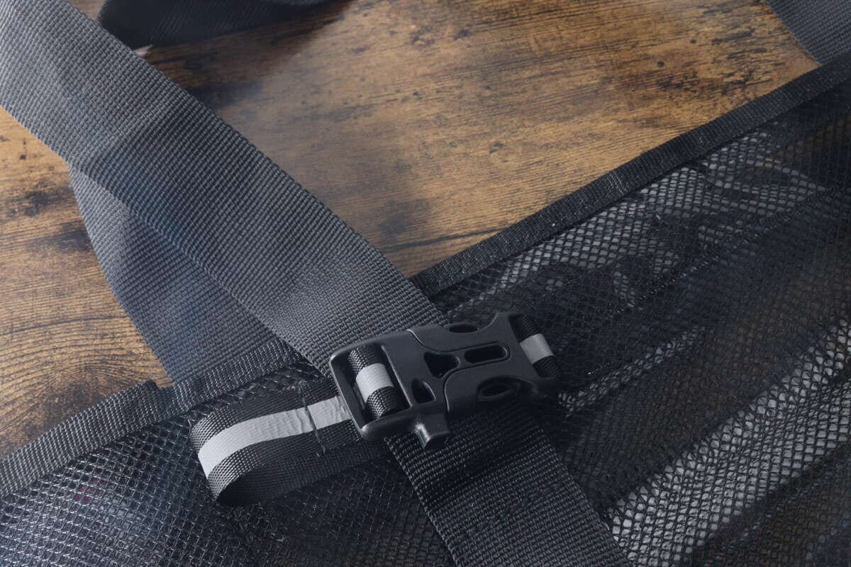 黒いバッグのストラップ部分に装着された反射材バックル 黒いバッグのストラップ部分に装着された反射材バックル