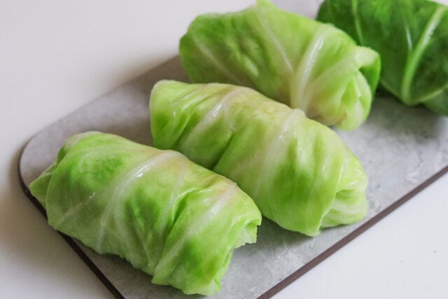 芯の分厚い部分を削ぎ、キャベツで中身が出ないよう包む。 芯の分厚い部分を削ぎ、キャベツで中身が出ないよう包む。