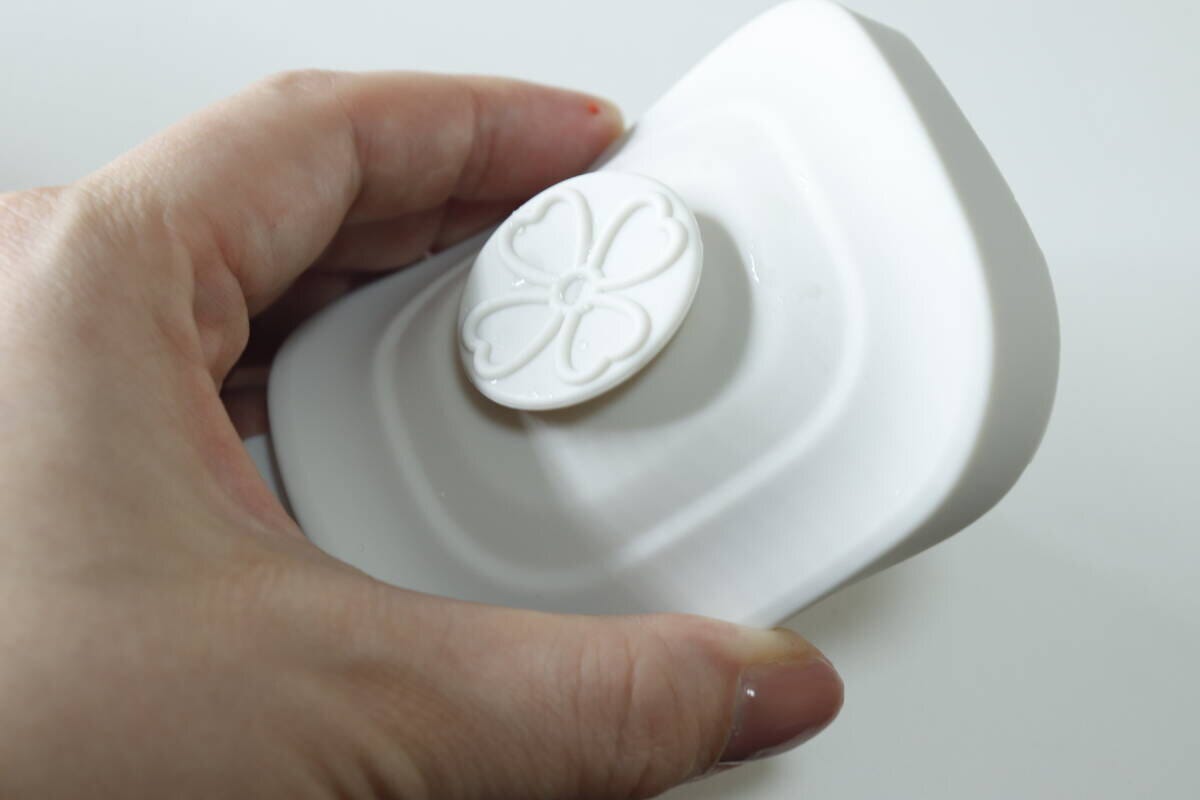 女性が白い保存容器の蓋にある桜の花のようなエア弁を押している