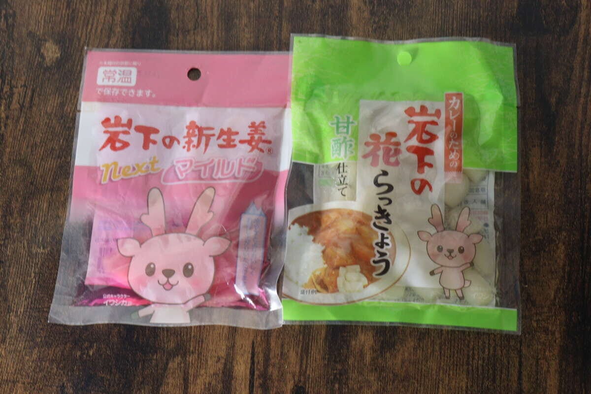 ピンク色の岩下の新生姜スライスnextと緑色の花らっきょうのパッケージが並んでいる ピンク色の岩下の新生姜スライスnextと緑色の花らっきょうのパッケージが並んでいる
